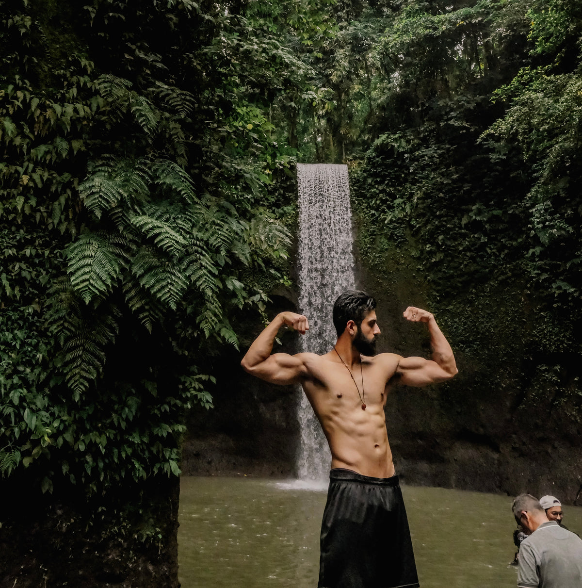 Taran posing in front of a jungle waterfall